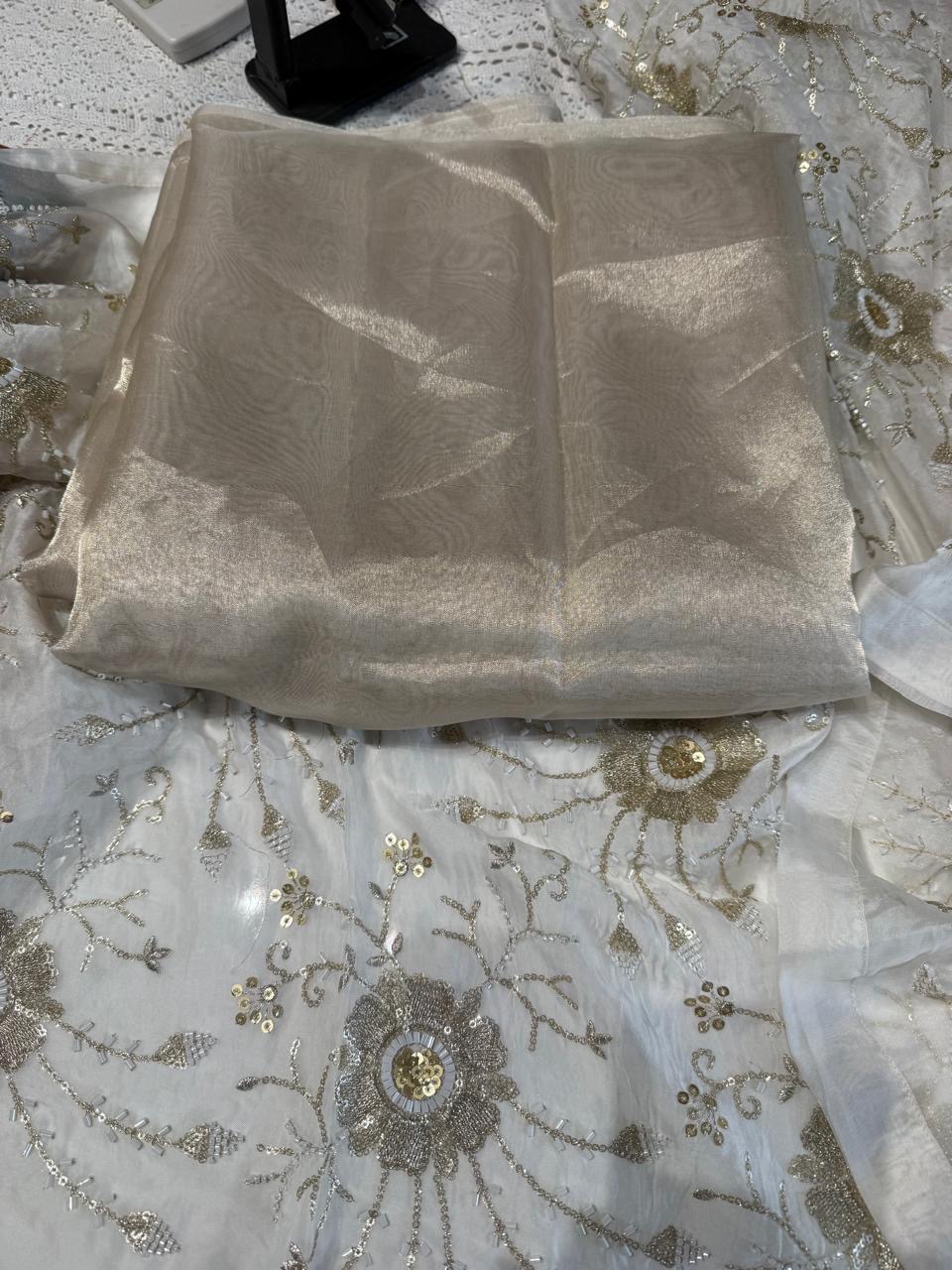 Soft ivory fabric with delicate flowers, vines and scattered embellishment.