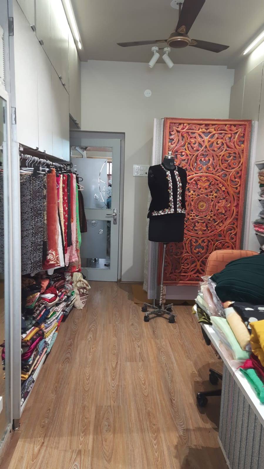 Garments, fabrics and a black embroidered outfit inside the boutique